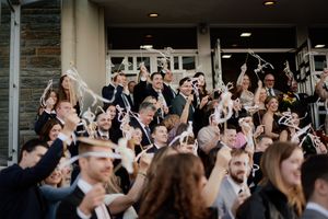 Large crowd of wedding guests gathered outside a stone building taking photos.