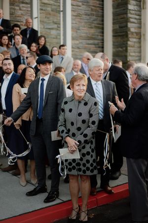 Wedding guests gathered on red carpet steps outside stone building.