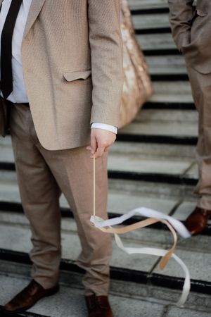 Detail shot of tan suit pants and dress shoes on stone steps.