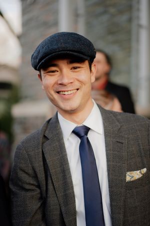 Stylish wedding guest wearing a flat cap, suit and navy tie with pocket square.