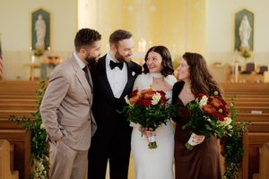 Wedding party members gathered in church with holiday greenery decorations.