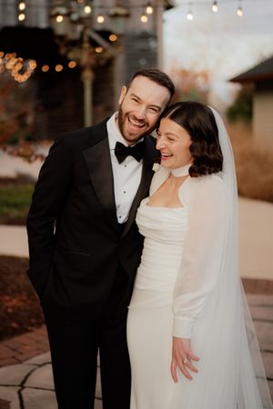 Elegant couple sharing intimate moments in formal wedding attire outdoors at dusk.