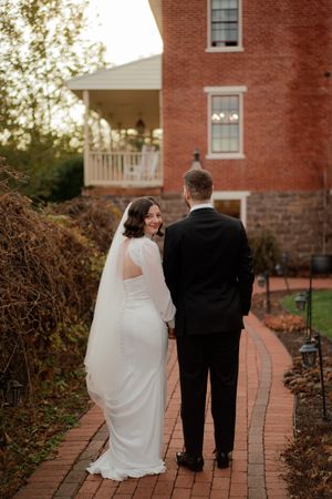 Couple walking along a brick path outside a historic red brick building.