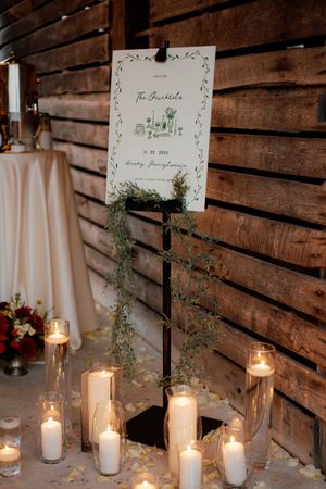 Rustic wedding decor featuring lit candles and greenery against wooden walls.