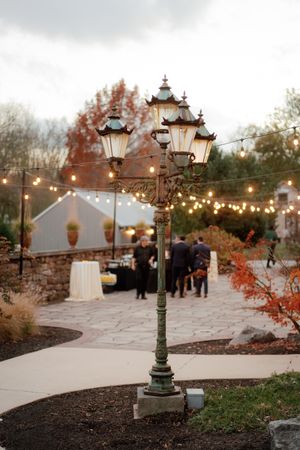 Evening reception venue with vintage lamp posts and string lights creating a romantic atmosphere.