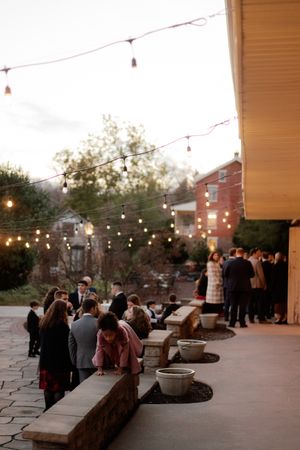 Outdoor evening reception venue with string lights and stone patio.