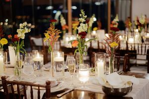 Elegant wedding reception table with floral centerpieces and glowing candles.