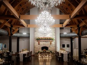 Elegant reception hall with exposed wooden beams and crystal chandeliers creating ambient lighting.