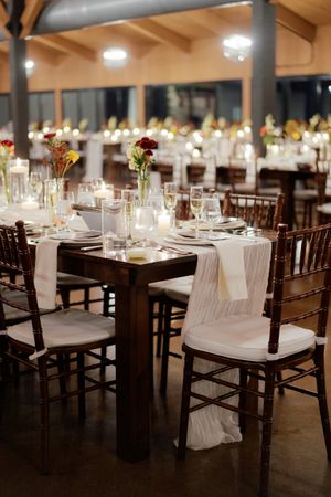 Reception hall set with dark wooden chairs and crisp white linens for an elegant dinner.
