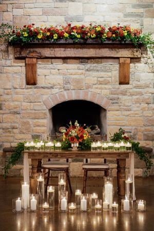 Stone wall decorated with candles and floral arrangements for wedding reception.