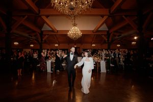 Wedding reception dance floor under warm lighting and crystal chandeliers.