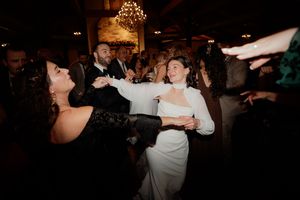 Wedding guests dancing and celebrating energetically on a dimly lit dance floor at the reception.