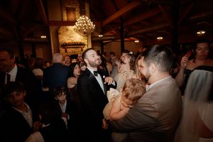 Wedding guests dancing and celebrating on a dimly lit dance floor at an elegant reception venue.
