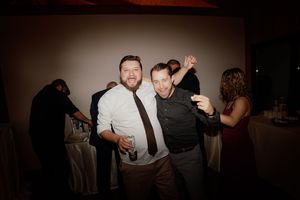 A dark and moody dance floor scene at a wedding reception with guests dancing in low lighting.