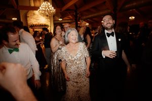 Guests enjoying themselves on a dance floor under warm chandelier lighting at an evening celebration.