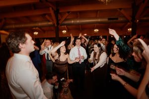 Wedding guests dance and celebrate on a dimly lit dance floor during an evening reception celebration.