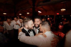 Celebratory dancing and embracing at a lively wedding reception with warm ambient lighting.