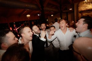 Wedding guests dancing and celebrating on a crowded dance floor at a reception.