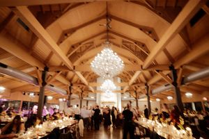 Elegant wedding reception venue with exposed wooden beams and crystal chandeliers.