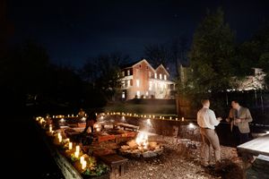Outdoor wedding reception at night with string lights illuminating the venue and walkway.