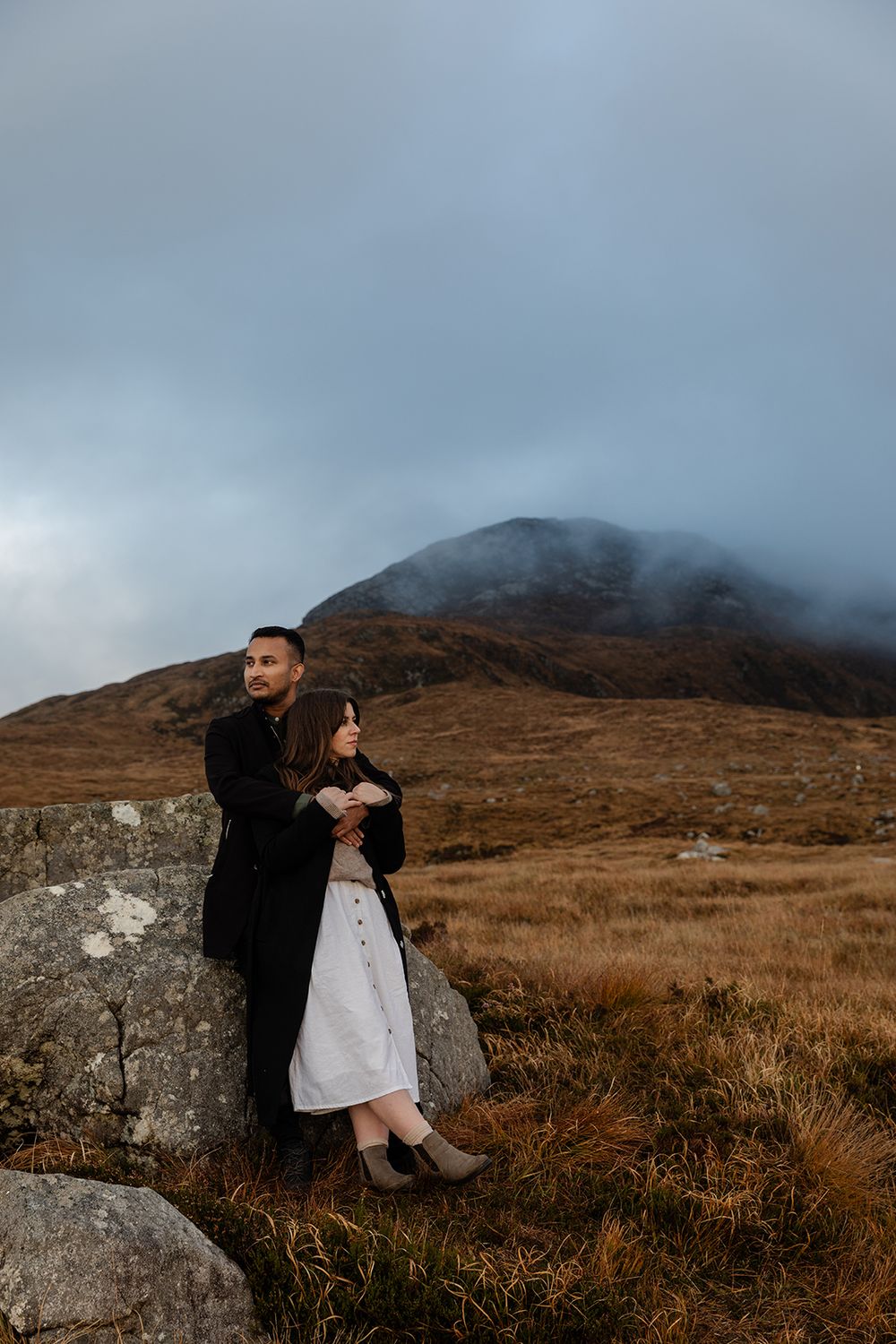 Couple hiking along rocky Connemara mountain ridge during engagement session