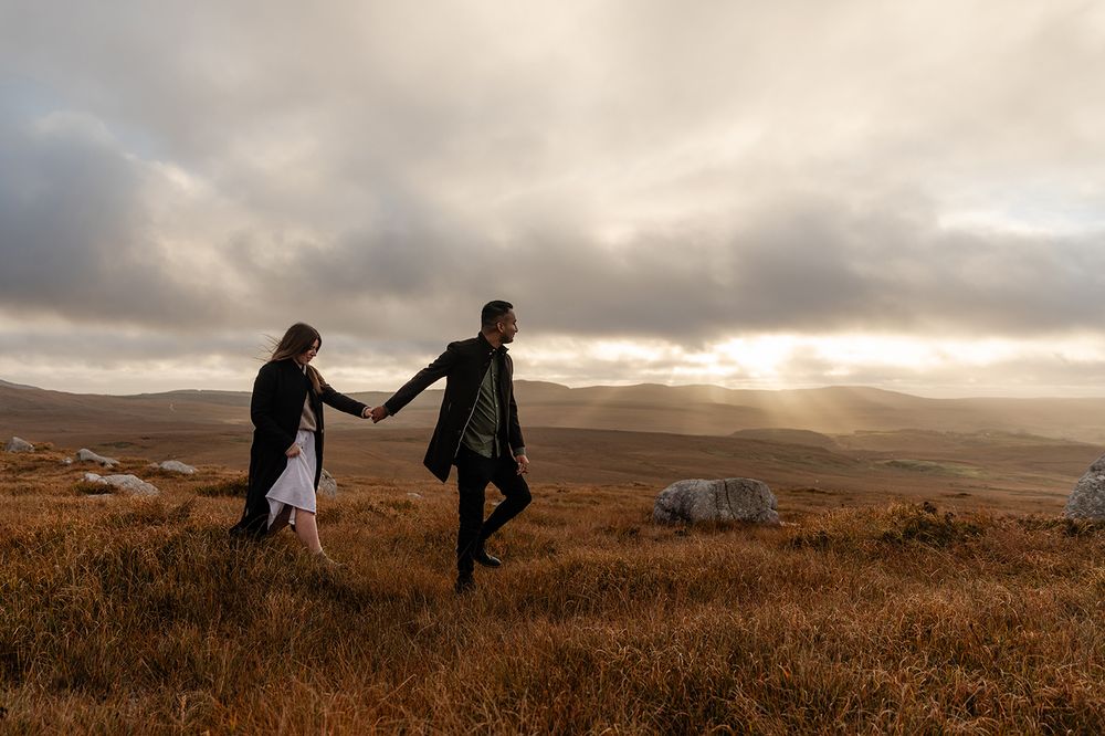 Couple walking hand in hand through Connemara mountain trail during elopement session