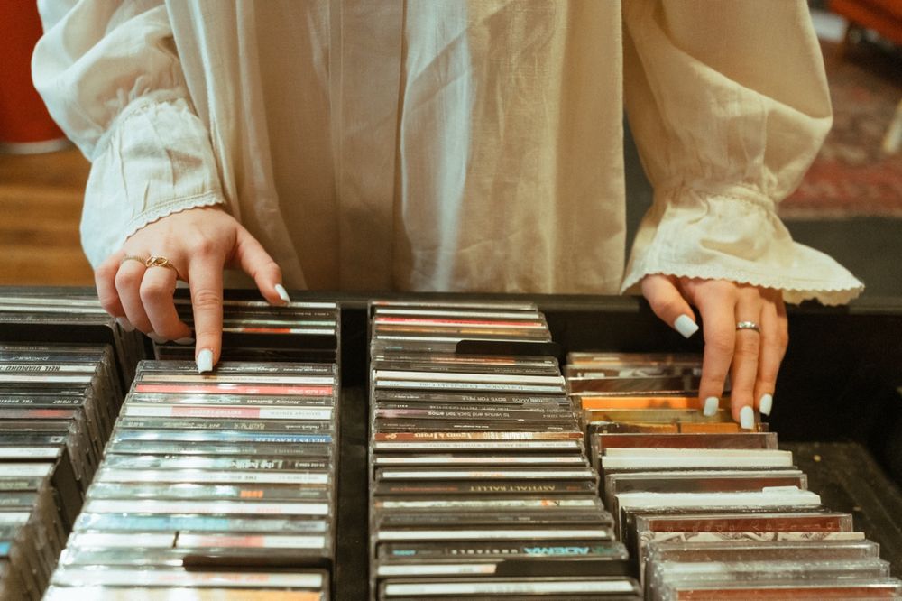 Person browsing through vinyl records in a store, flipping through album covers in storage bins.