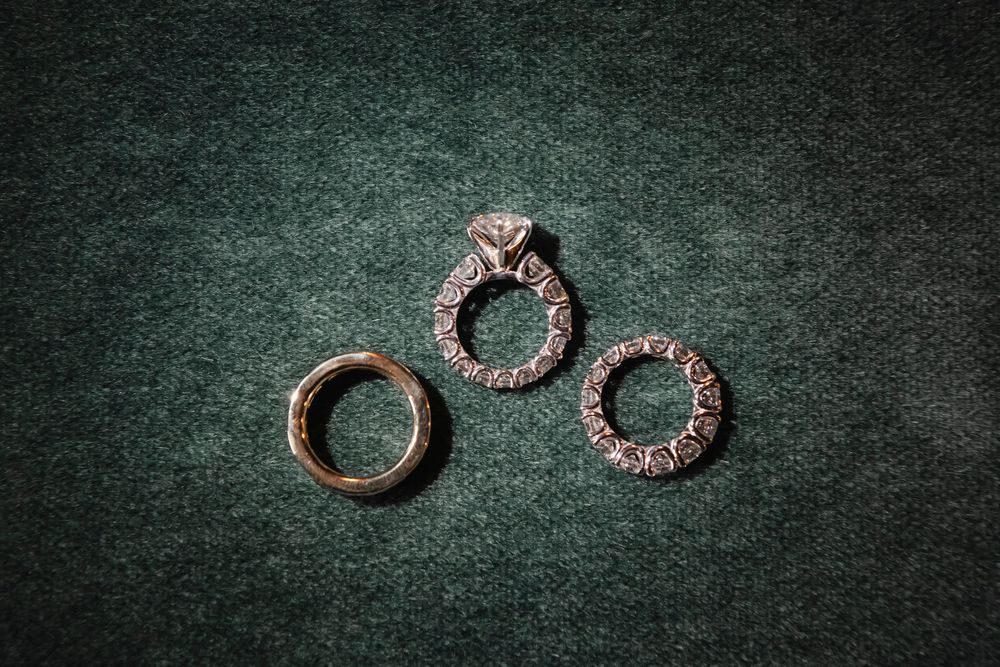 Three vintage-style wedding rings arranged on dark green velvet background.