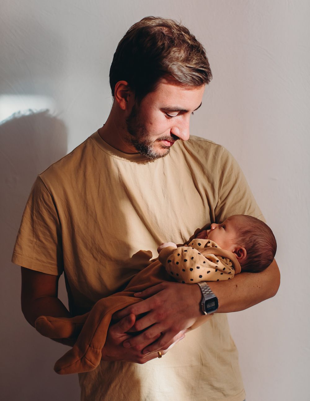 A series of tender moments between parent and newborn baby shown in soft lighting against a neutral background.