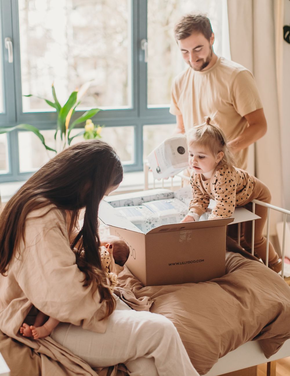 Family members unpack cardboard moving boxes together in a bright, modern room with large windows.