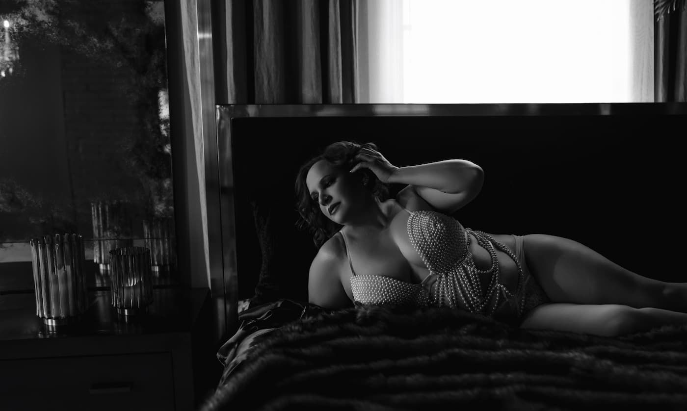 Black and white artistic portrait photo showing someone lying down in dramatic shadows and lighting.