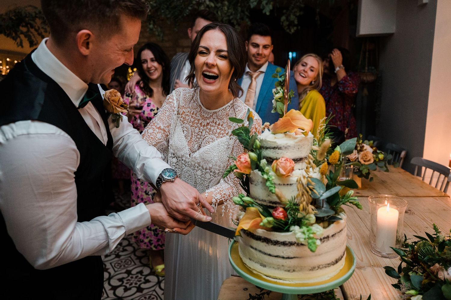 Couple cutting their floral-decorated wedding cake at an evening reception.