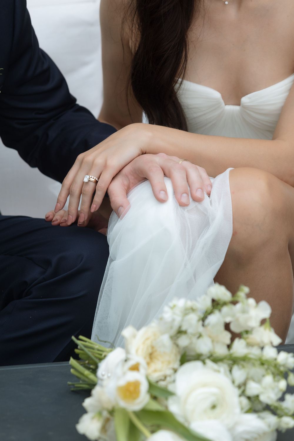 Close-up sequence of hands adjusting a white wedding dress with a bouquet of white flowers in the frame.