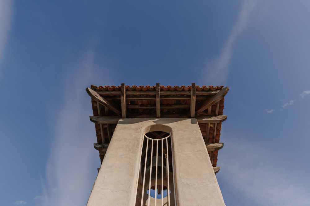 Traditional Middle Eastern wind tower architecture against blue sky with white stone walls and wooden details.