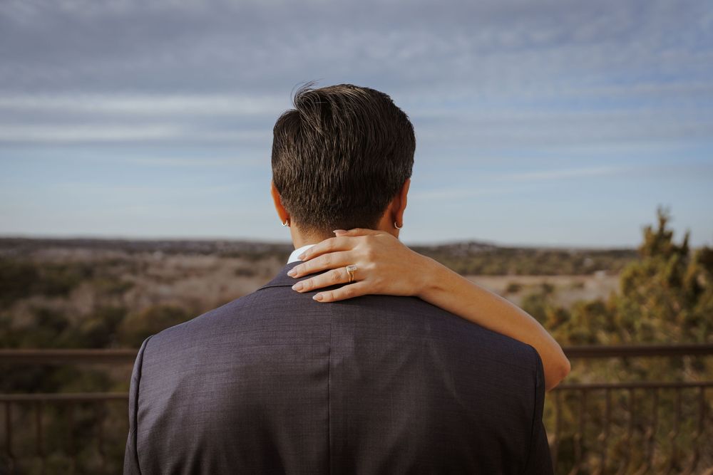 Couple sharing a tender moment while overlooking a scenic desert landscape at sunset.