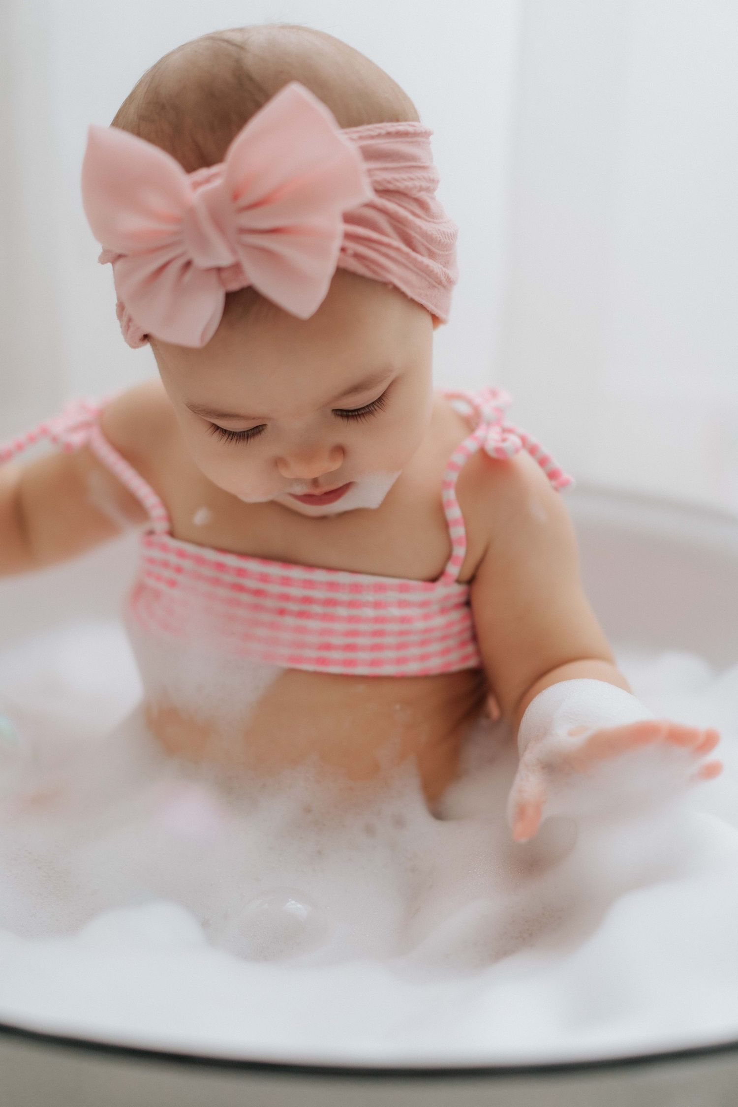 Series of cake smash photos with white dress, teddy bears, balloons and orange backdrop for baby milestone celebration.
