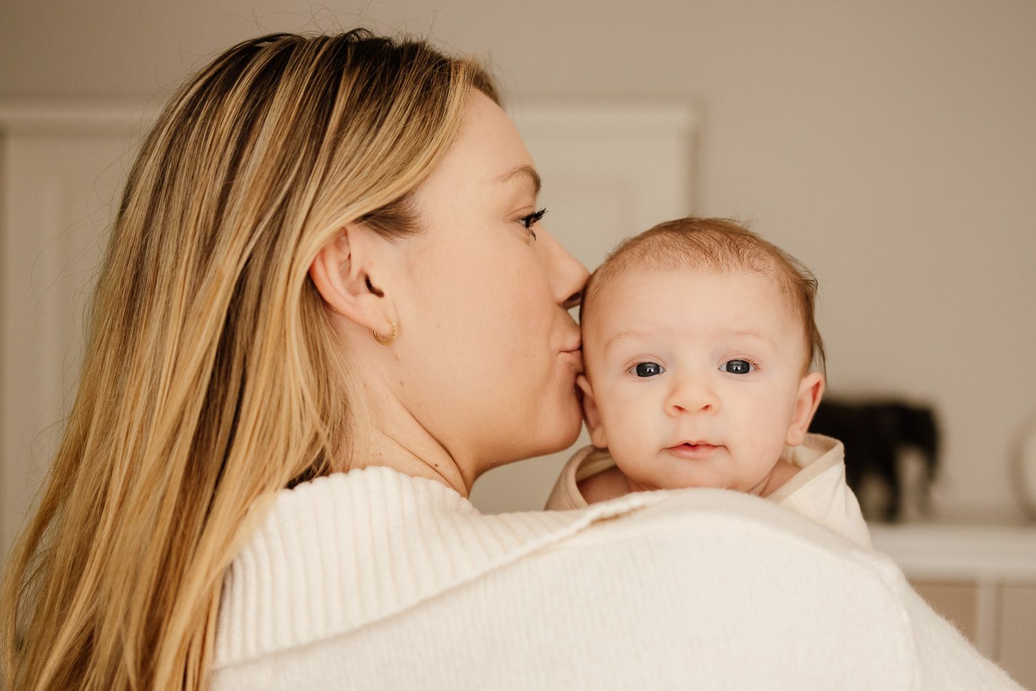 Baby looks into the camera over mom's shoulder