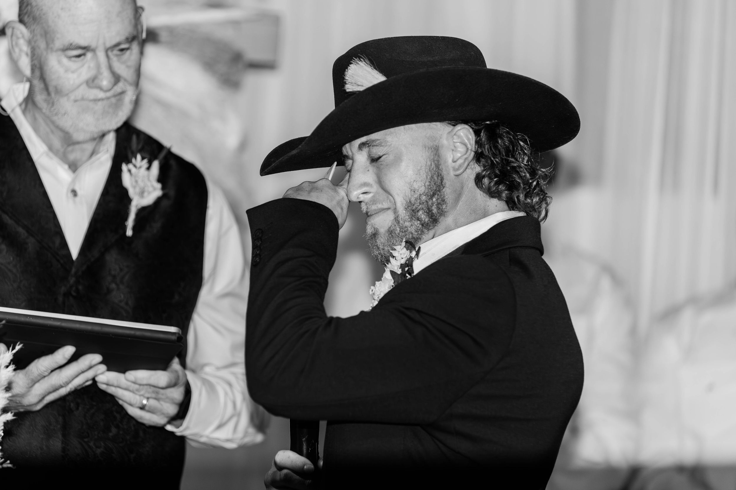 Black and white photo of officiant in cowboy hat during wedding ceremony.