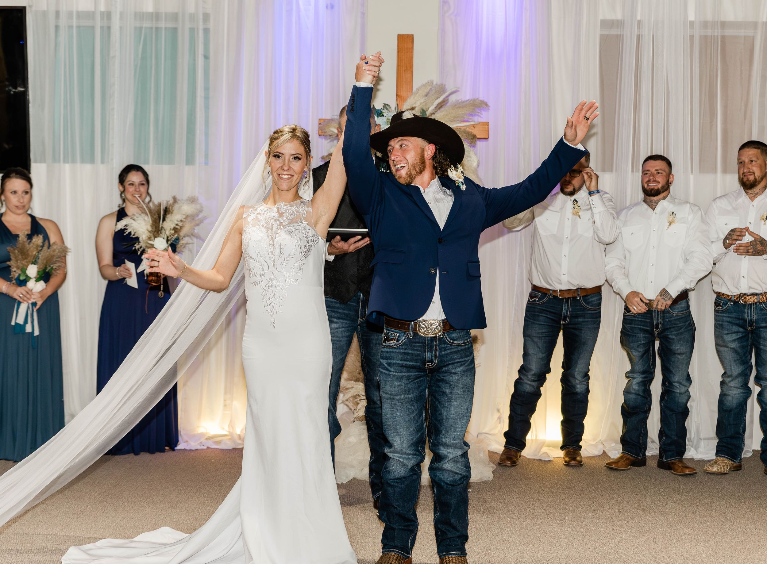 A joyful wedding celebration with the couple raising their arms in celebration on the dance floor.
