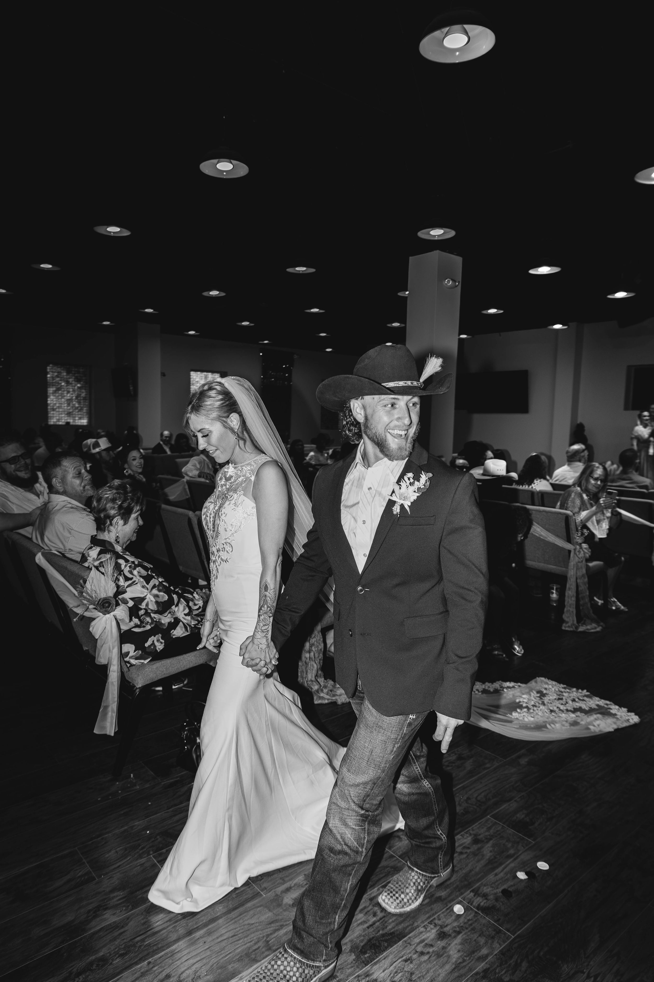 A western-themed wedding reception with the couple walking through a crowded venue.