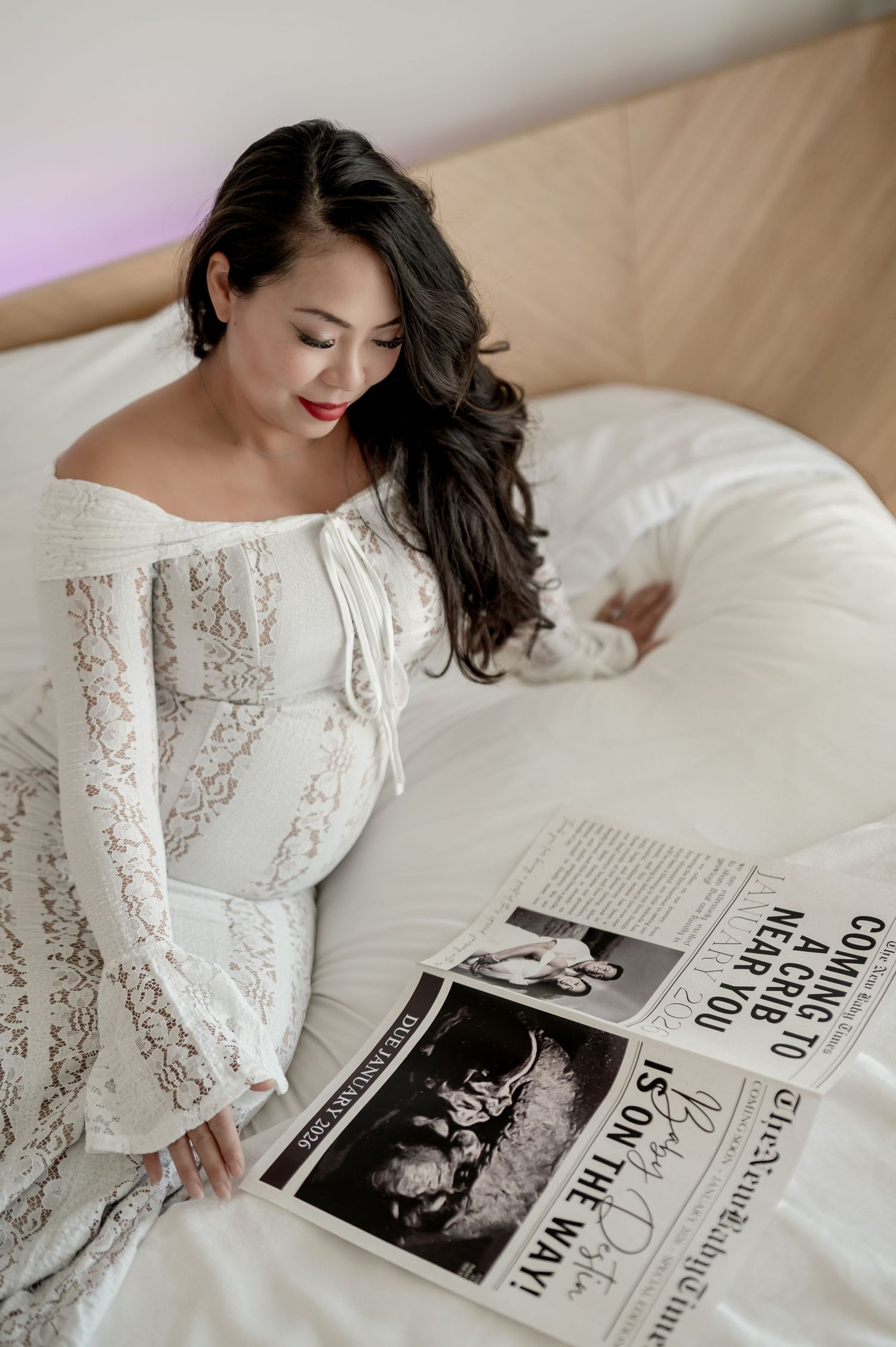 A person in white lace lounges on a bed while reading a black and white magazine spread.