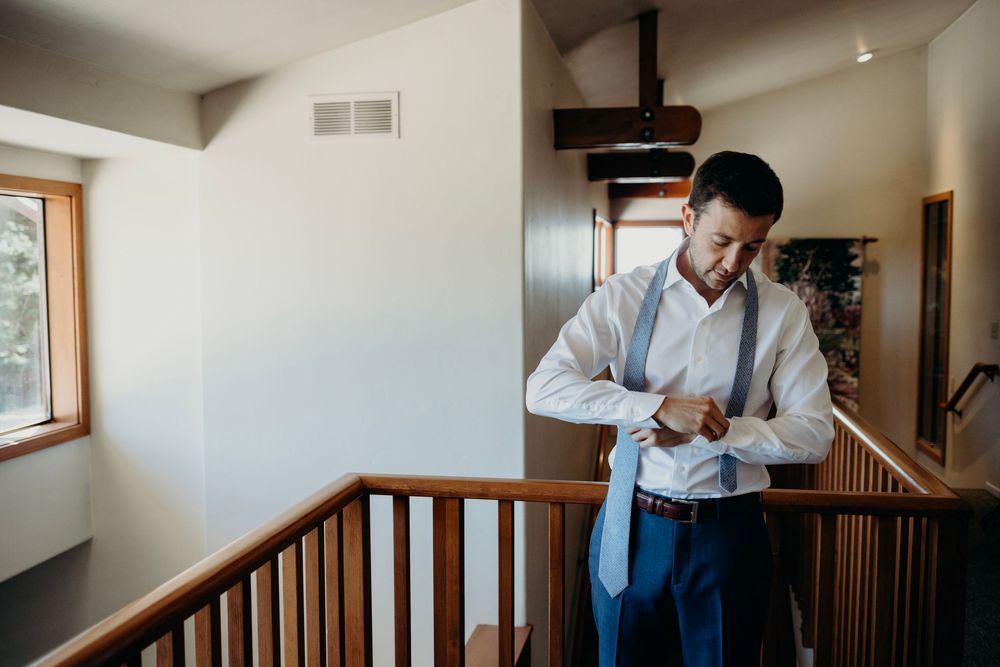 A person in a white dress shirt stands at the top of a wooden staircase in a modern home interior.