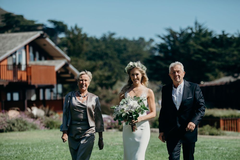 A group of wedding party members walking and laughing together on a sunny day outdoors.