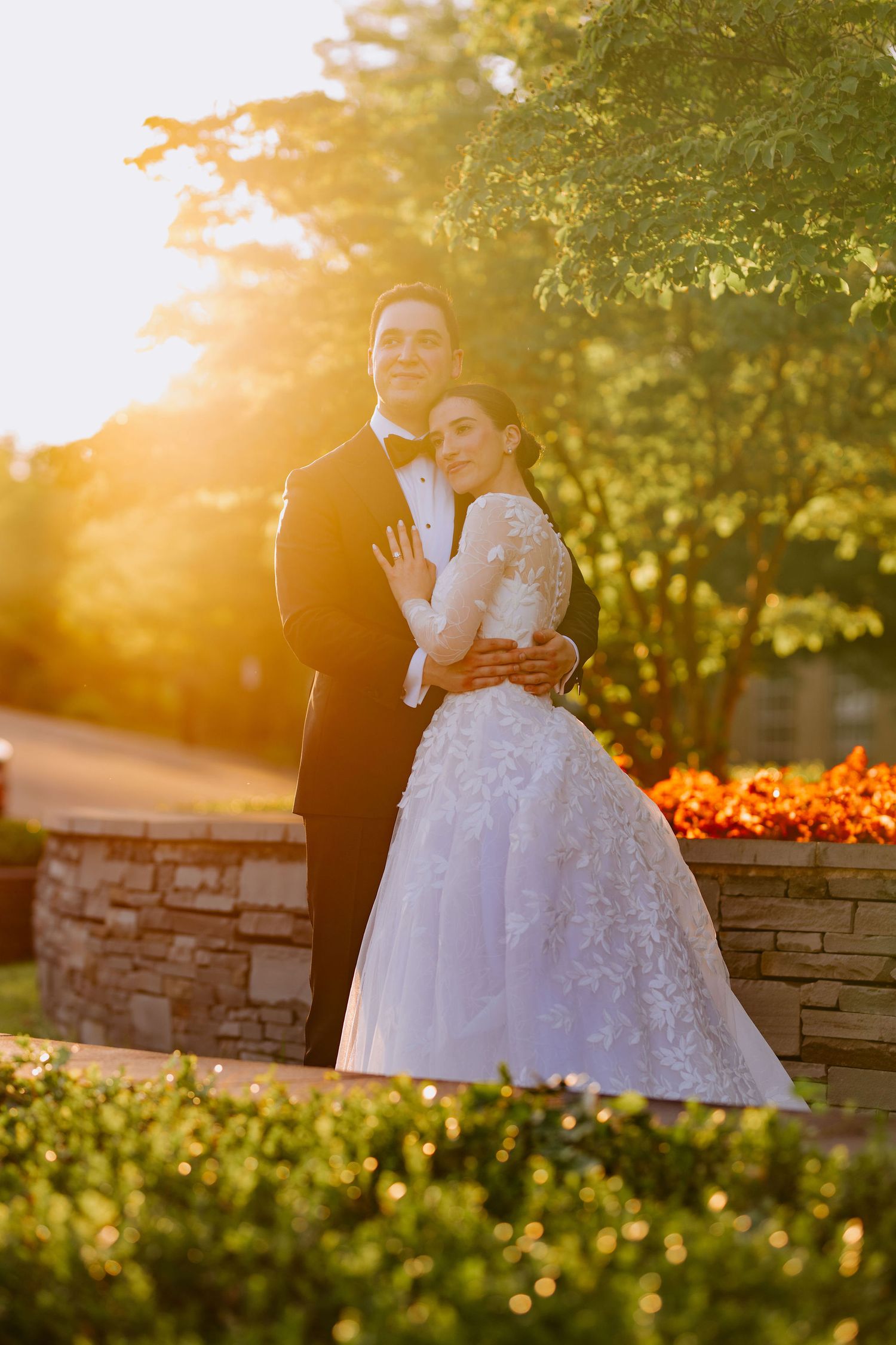 A couple embraces during a romantic golden hour photoshoot in a lush garden setting.