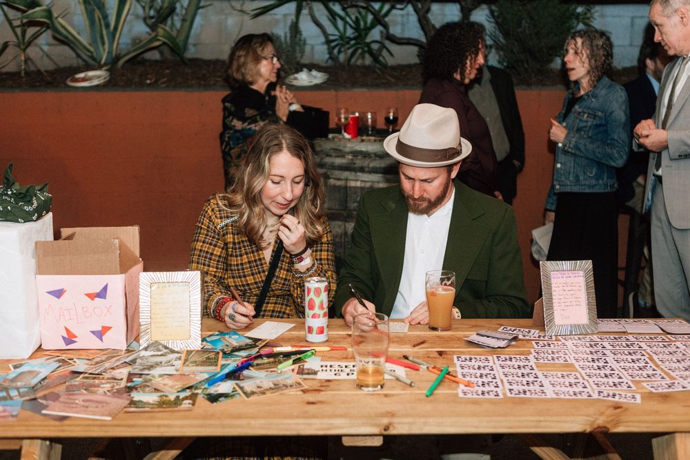 Guests sign bride and groom's guest book while eating tacos and drinking beer for laid back wedding reception.