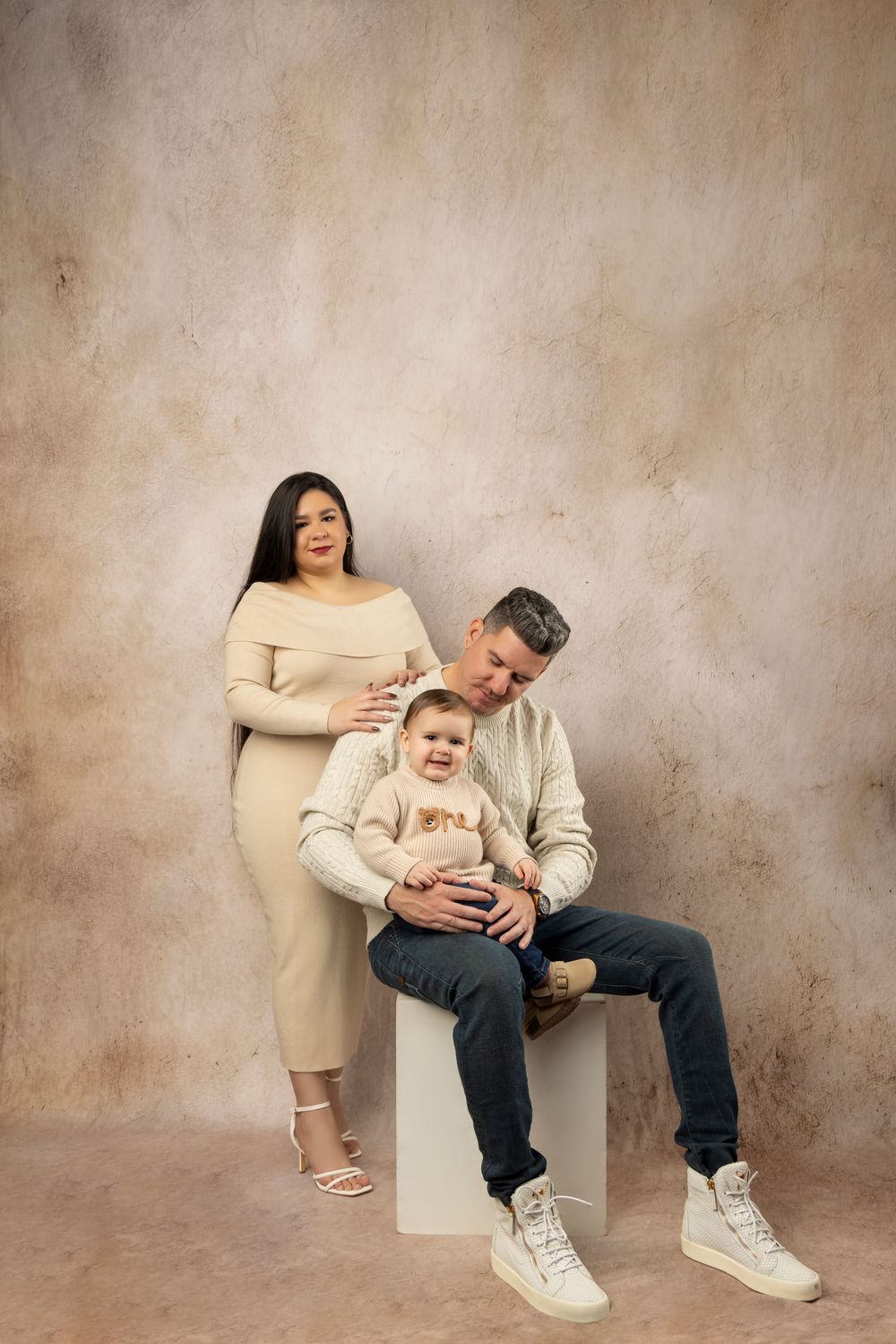 Modern family portrait series in neutral tones against textured beige wall.