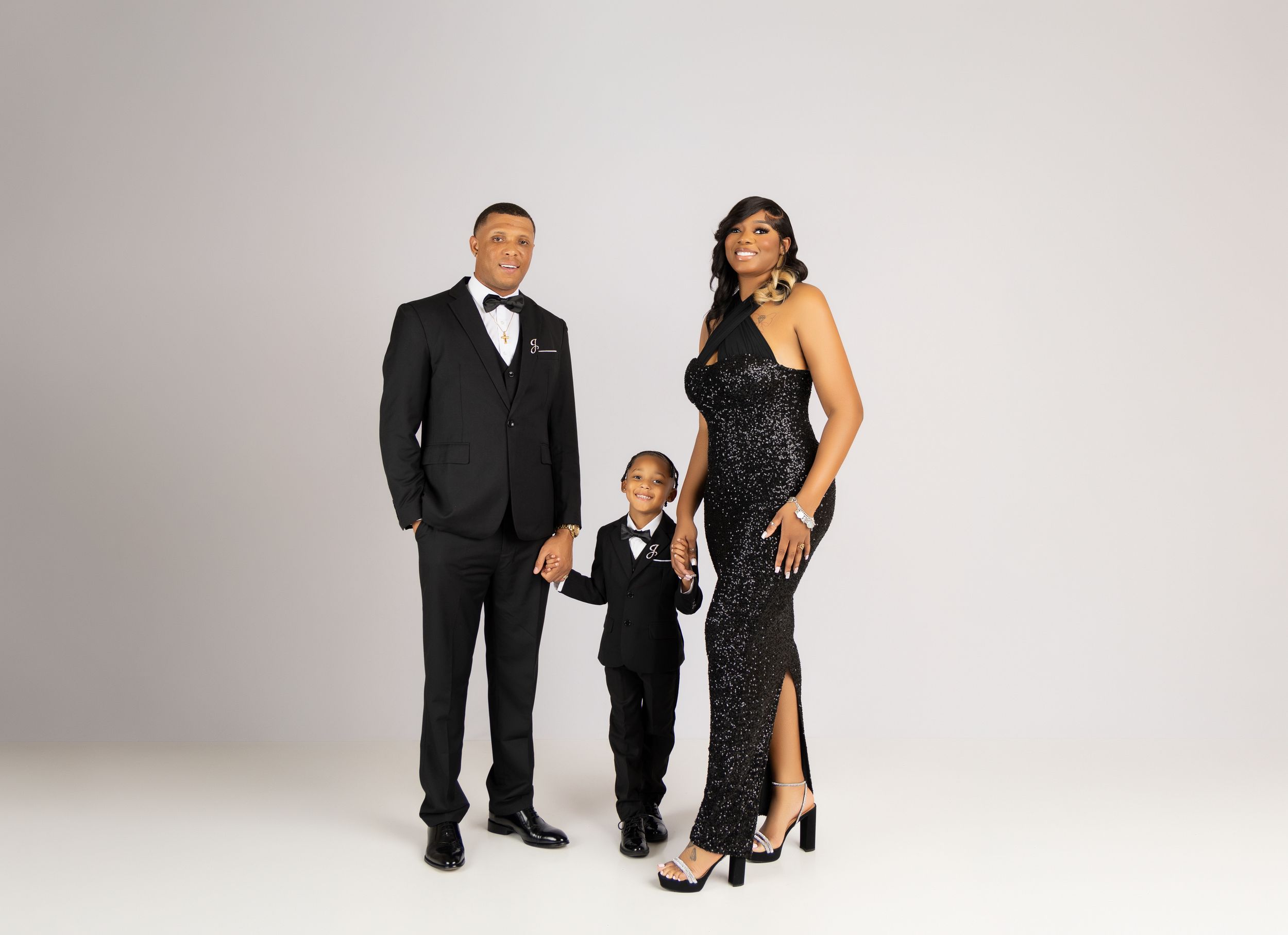 Formal family portrait series in black and white attire against light background.