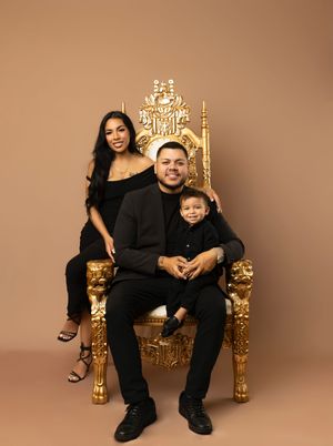 Studio portraits on ornate gold throne chairs against brown backdrop.