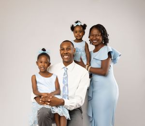 Family portrait session in coordinated white outfits against a light background.