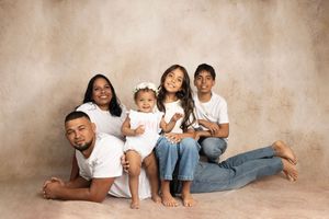 Casual family photo series with everyone wearing white shirts and jeans against beige backdrop.